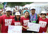 Sanjay Shah, on right wearing a medal, with his wife and daughters who are holding signs that say Go SanJay at the triathlon